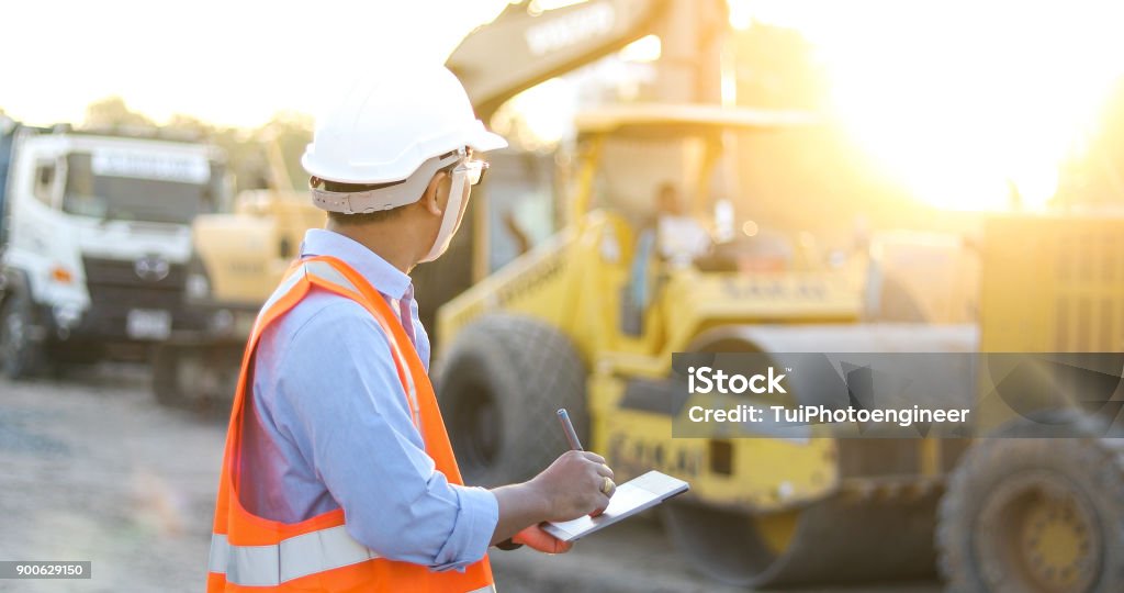 Asian engineer with hardhat using  tablet pc computer inspecting and working at construction site Construction Site Stock Photo