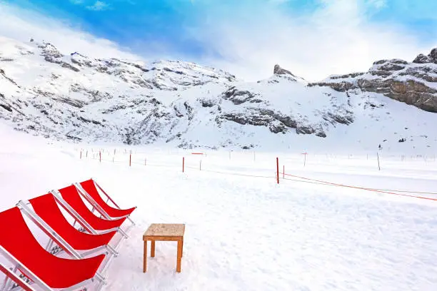 Red deck chairs on a mountain restaurant terrace on a sunny day in winter. Trubsee in Engelberg, Switzerland
