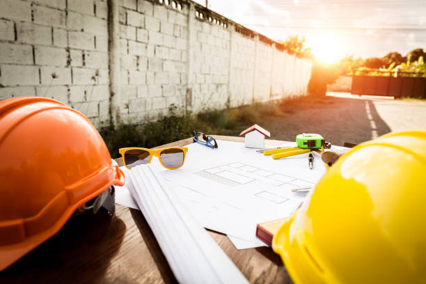 istock Engineer desk closeup, helmet, house plan with equipment 900647956