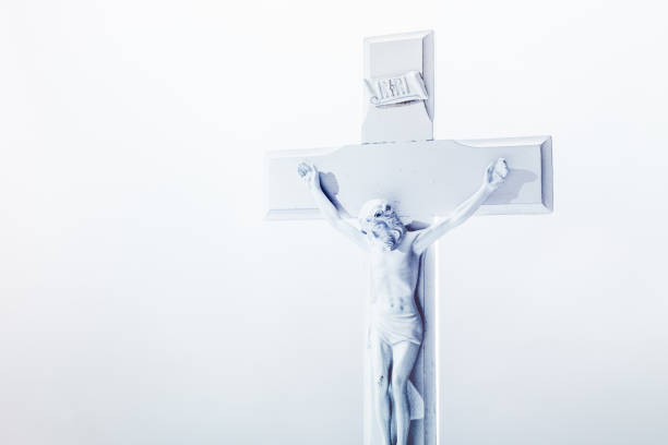 A depiction of Jesus Christ on a cross as conveyed in the Christian / Catholic Bible.  The crucifix and background are white in color.  Horizontal background element with copy space.