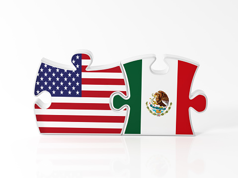 Jigsaw puzzle pieces textured with American and Mexican flags on white. Horizontal composition with copy space. Clipping path is included.