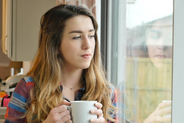 istock Sad young woman drinking coffee at home 900664802