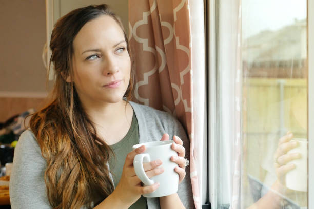 istock Anxious woman drinking coffee and looking out window 900664812