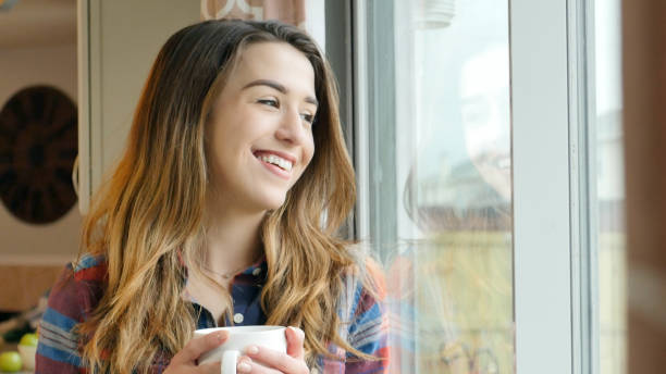 istock Young woman smiles as she drinks morning Coffee 900664818