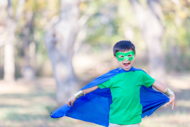 istock Little boy pretends to fly dressed as superhero 900664874
