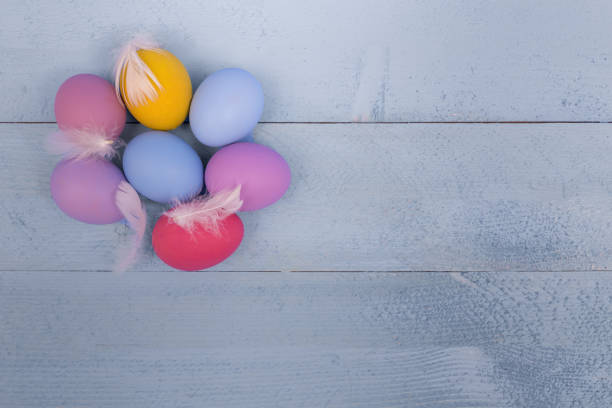 istock Colorful Easter eggs on a blue wooden board with feathers 900699760