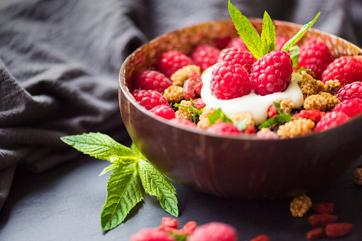 Delicious breakfast with organic raspberries and mulberries served in a coconut bowl