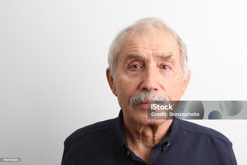 An old man looking at camera with a serious facial expression An old man looking at camera with a serious facial expression on white background Portrait Stock Photo