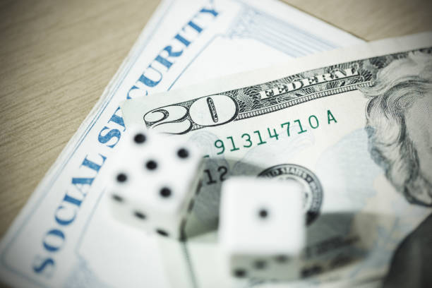 Social Security Card with Currency and Dice Close-up of an old Social Security Card with US currency and dice. social security social security card identity us currency stock pictures, royalty-free photos & images