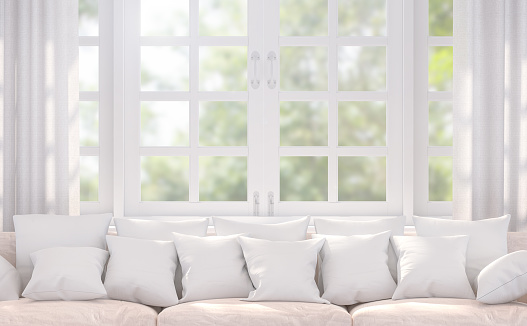 Modern white living room 3d rendering image.Decorated with beige sofa. There are many pillows.Behind sofa has white windows look out to see nature.