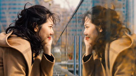 Hermosa chica China mirando su reflejo en el vidrio. photo