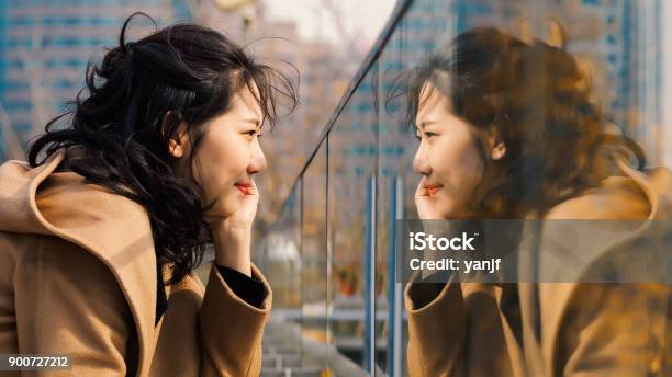 Beautiful Chinese Girl Looking At Her Mirror Image In Glass Stock Photo - Download Image Now