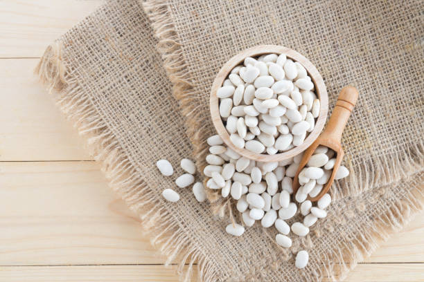 istock white bean in wood cup on sack background 900730832