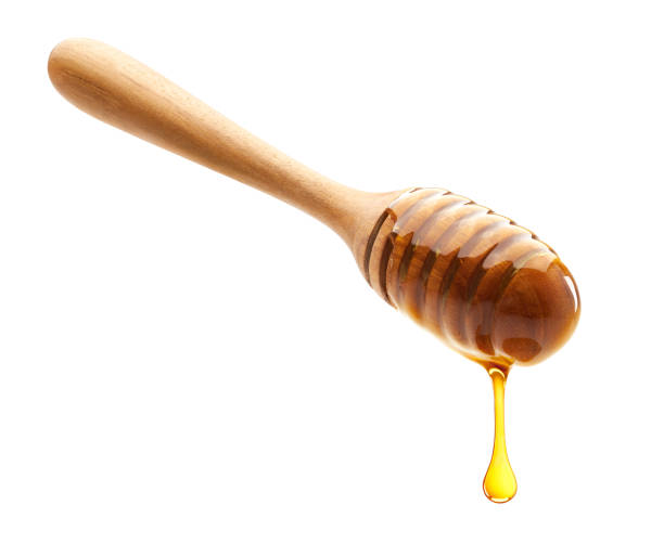 istock Honey dripping from dipper isolated on white background 900746530
