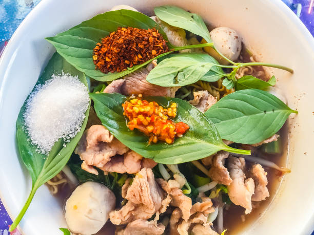 Popular street food in Thailand, Spicy pork noodle that consisted of pork ball, pork meat, basil or thyme, bean sprouts, morning glory, noodle and creamy soup which favouring with sugar, fish sauce, chilli and vinegar marinade comida callejera de popular en tailandia, tallarines del cerdo que consisten en bolas de carne de cerdo, carne de cerdo, albahaca o tomillo, brotes de soja, gloria de mañana, tallarines y sopa cremosa marinada que favorecer con el azúcar, salsa de pescado, ají y vinagre