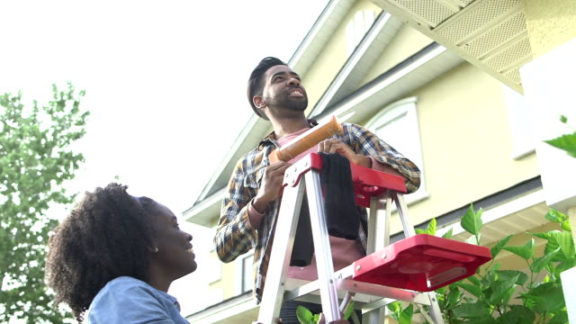 Couple doing some home repairs outside house