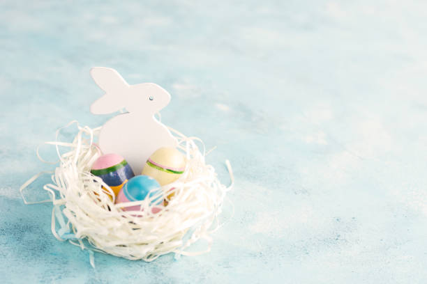 istock White paper nest with three vintage Easter eggs and bunny on blue background 900787144