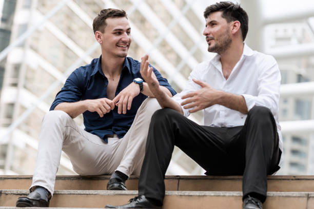 istock Two happy businessmen sitting down on concrete stairs. 900787164