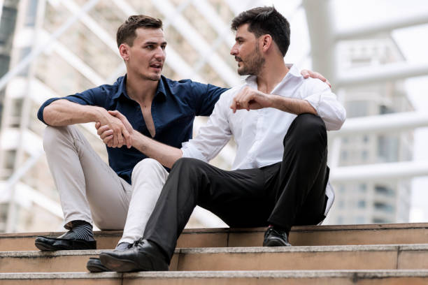 istock Two happy businessmen sitting down on concrete stairs. 900788018