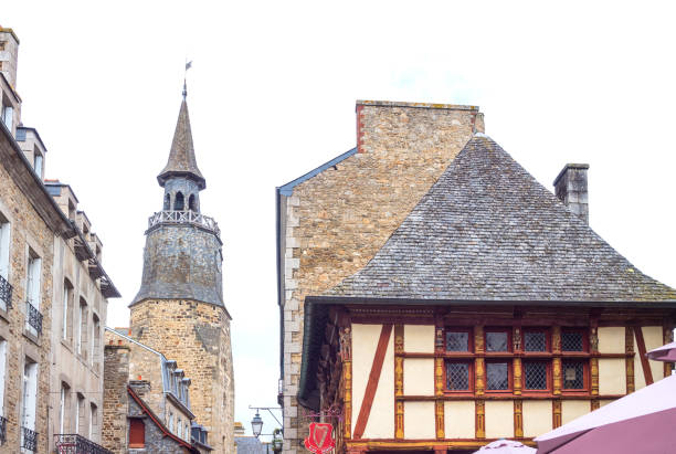 Dinan, France - August 8, 2017: The ancient houses of the country center with the medieval Clock Tower in the background