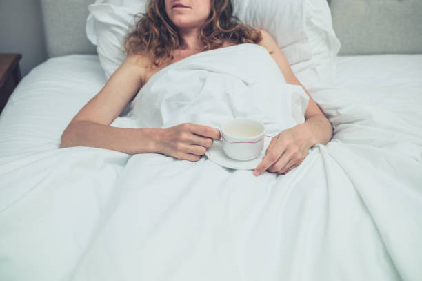 istock Young woman drinking tea in bed 900799444