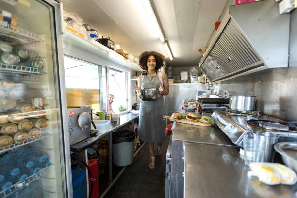 istock Smiling female food van worker making sandiches 900799714