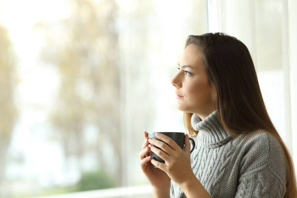 istock Pensive serious woman looking through a window 900801004