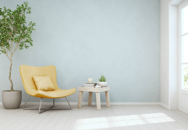 plante d’intérieur et la table basse sur plancher en bois avec fond de mur de béton bleu vide, chair jaune près de la porte dans un salon lumineux de maison scandinave moderne - decor yellow white blue photos et images de collection