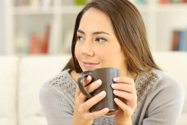 istock Pensive woman holding a coffee mug looking at side 900807328