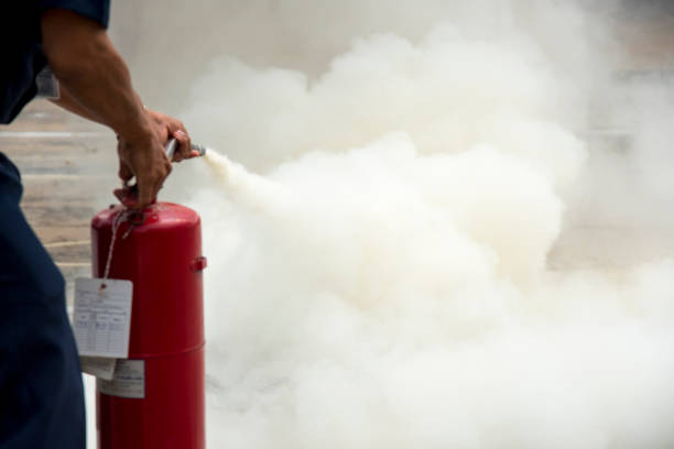 A man practises how to use a fire-extinguisher A man practises how to use a fire-extinguisher for use as a background. extinguishing photos stock pictures, royalty-free photos & images