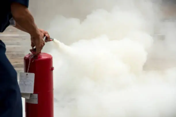 A man practises how to use a fire-extinguisher for use as a background.