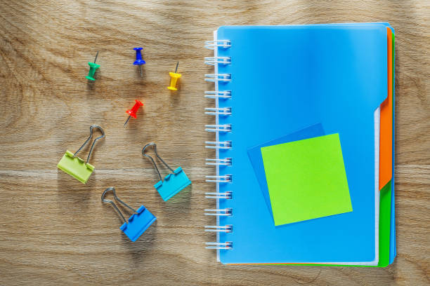 istock Notepad pen drawing pins paper clips on wooden board 900807958
