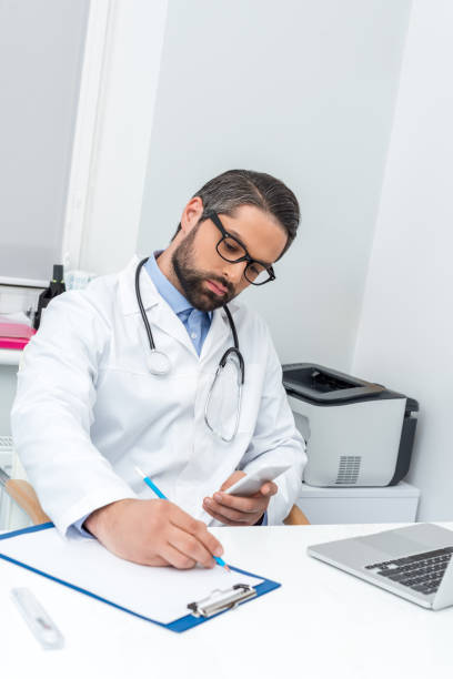 istock doctor using smartphone and writing in clipboard 900811518
