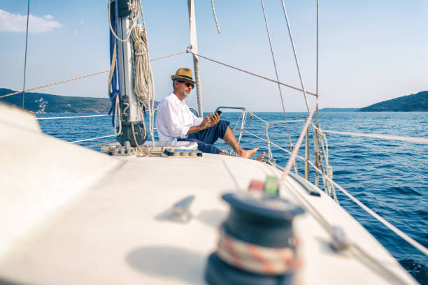 istock Man on a luxury yacht looking at a smartphone 900811636