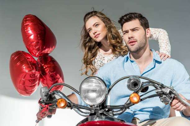istock couple with red balloons sitting on scooter 900819992