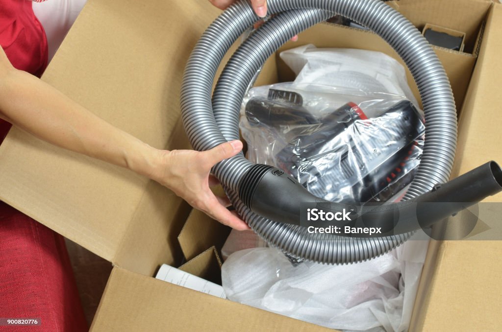Opening a new vacuum cleaner Unpacking a new modern vacuum cleaner and its elements Allergy Stock Photo