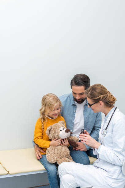 doctor giving syrup to teddy bear young doctor giving syrup to teddy bear of little girl doctor utensils stock pictures, royalty-free photos & images