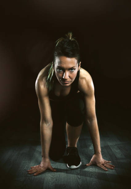 istock Athletic woman ready to run over dark background 900824854