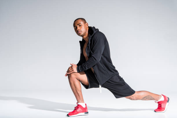 istock sportsman stretching and looking at camera on grey 900825142