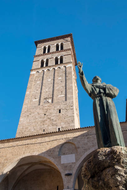 Rieti (Italy), the cathedral Rieti, Italy - July 17, 2017: Rieti (Lazio, Italy): exterior of the medieval cathedral. The belfry and a bronze statue rieti stock pictures, royalty-free photos & images