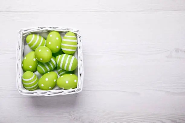 Photo of Colorful easter eggs in white basket. Easter background with copy space