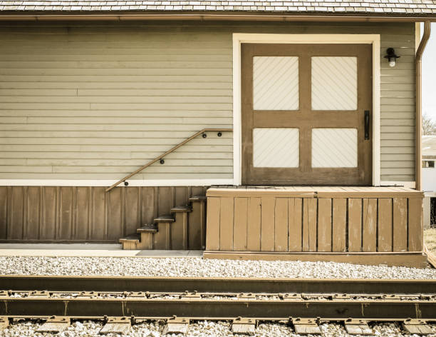 Façade of historical train station with empty platform and train tracks in the foreground in Midwestern USA.