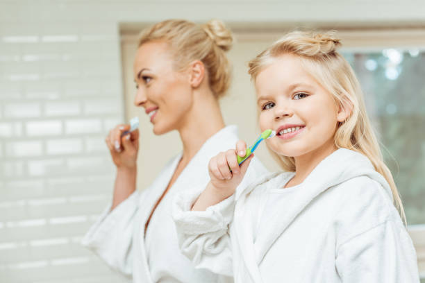 istock mother and daughter brushing teeth 900833486