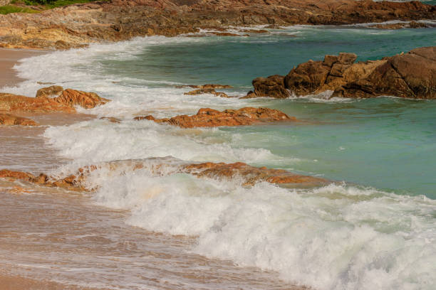 istock Beautiful white bubbles created on the beach by ocean waves on seashore. The ocean waves hit the rocks on the beach 900833624