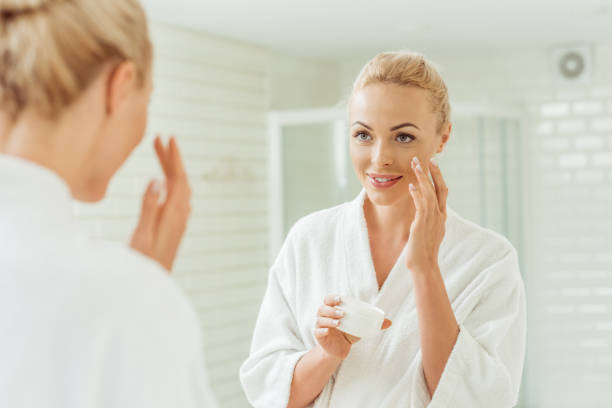 istock woman in bathrobe applying face cream 900839934