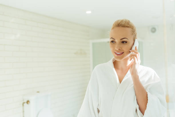 istock woman in bathrobe talking on smartphone 900840144