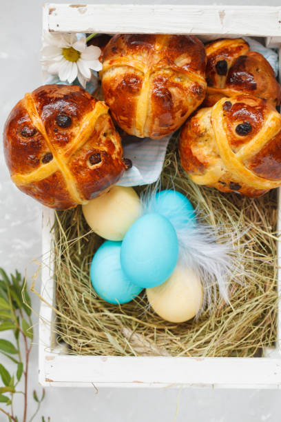 istock Easter cross buns in a wooden box, painted eggs. Light background, copy space, top view. Easter food concept. 900841772