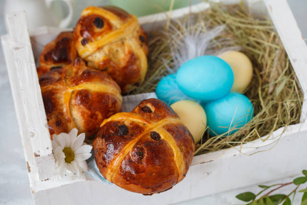 istock Easter cross buns in a wooden box, painted eggs. Light background, copy space, Easter food concept. 900841892