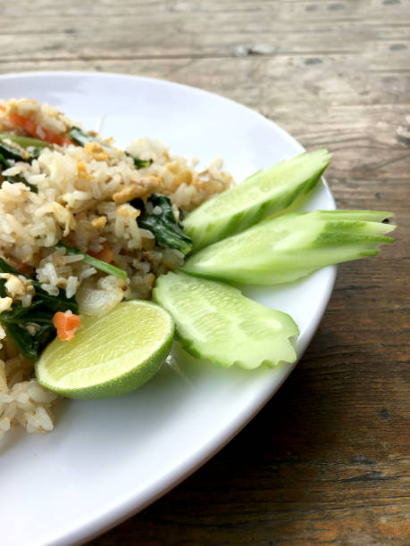 istock Asian fried rice with mackerel; egg and vegetable in white dish serve with slide cucumber on wooden background. Thai style food. 900845170
