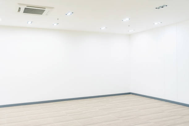 istock Empty room with whitewashed floating laminate flooring and newly painted white wall in background 900845404